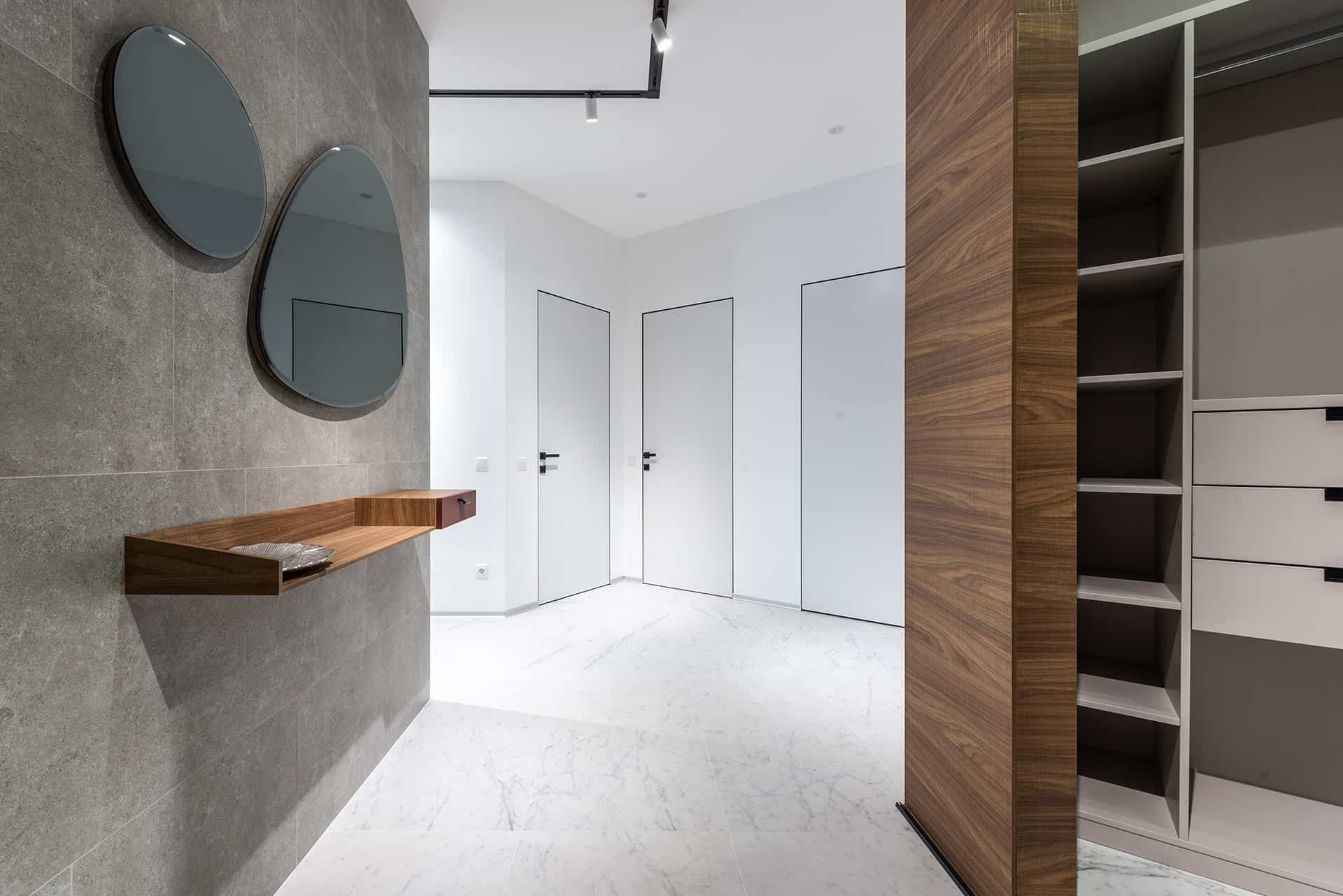 Modern hallway with white doors, gray tiled wall, and marble floor.